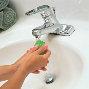 Gros plan de mains de femme se lavant avec du savon dans un lavabo.
